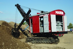 The power cord for the National Construction Equipment Museum’s Marion Model 21 Electric Shovel is visible on the ground behind it, and the AC/DC motor/generator that powers the motors can be seen inside the back doors.