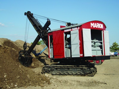 The power cord for the National Construction Equipment Museum’s Marion Model 21 Electric Shovel is visible on the ground behind it, and the AC/DC motor/generator that powers the motors can be seen inside the back doors.