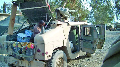 A technician servicing/installing the system, working inside the right rear quarter of the vehicle.