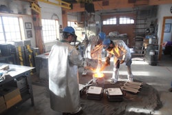 Joyworks Studio personnel inoculating a ladle of ductile iron.
