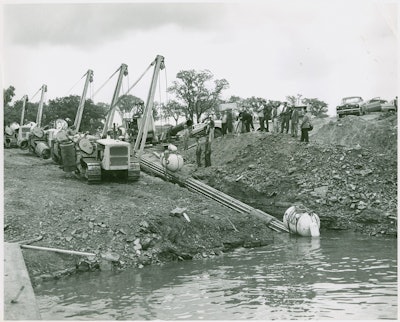 The ability of sidebooms and pipelayers to walk with a long strand of pipe makes possible a project like this. Bechtel Corporation is walking a 600-foot strand of pipe into the Niagara River for the Tennessee Gas Transmission Company on September 11, 1954. This was the first pipeline to cross the Niagara, and a fleet of Cat MD7s, equipped with extra counterweights, is doing the honors. The MD7 was a very popular sideboom; fleets of them still turned up in pipeline auctions into the early 2000s.