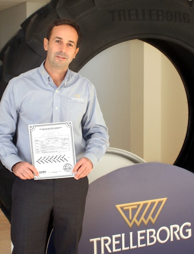 Andrea Masella standing next to the first tire produced at Trelleborg’s Spartanburg, SC plant holding the tire's “birth certificate.”