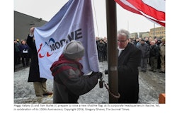 Modine President and CEO Tom Burke (right) prepare to raise the flag with the company's 100th anniversary graphic and logo at its headquarters.
