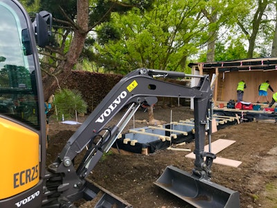 The electric excavator digging the foundations of the garden’s main structure.