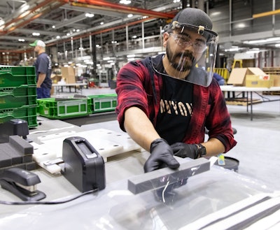 Jose Martinez aids with assembly of face shields at the John Deere Seeding Group.