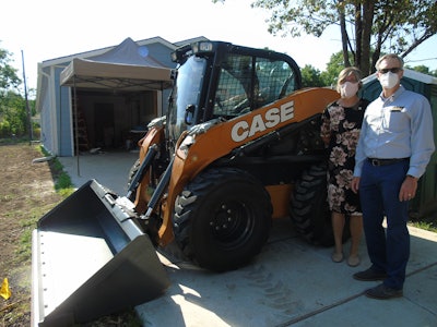 Ann Fox with Habitat and Troy Williams with CASE stand next to the donated excavator.