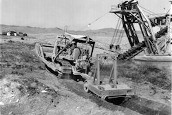 A LeTourneau Double-Drum Power Control Unit enables this Cat D7 to operate both a dozer and a pull ripper. The scene is a placer gold mine operated by Parker Brothers Corporation and Last Chance Gulch, near Helena, MT.