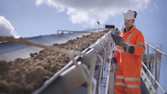 A Continental employee carefully watches and checks the workings of a mining conveyor.