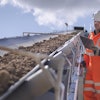 A Continental employee carefully watches and checks the workings of a mining conveyor.