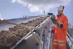 A Continental employee carefully watches and checks the workings of a mining conveyor.