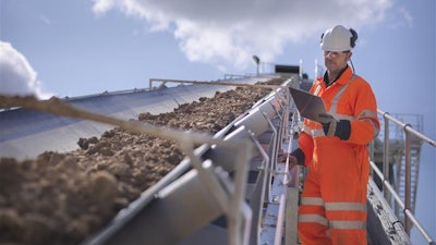 A Continental employee carefully watches and checks the workings of a mining conveyor.