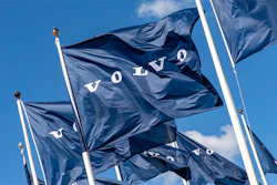 Volvo corporate flags waving against blue sky with white flagpoles