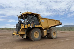 Yellow Caterpillar 715 articulated dump truck on desert terrain with mountains in background