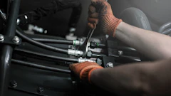 Mechanic wearing brown gloves working on engine components with tools during assembly or maintenance
