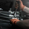 Mechanic wearing brown gloves working on engine components with tools during assembly or maintenance