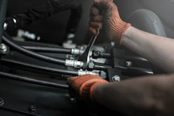 Mechanic wearing brown gloves working on engine components with tools during assembly or maintenance