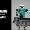 AGCO and Agility robotic agricultural robot with turquoise chassis and black mechanical arms holding farming equipment