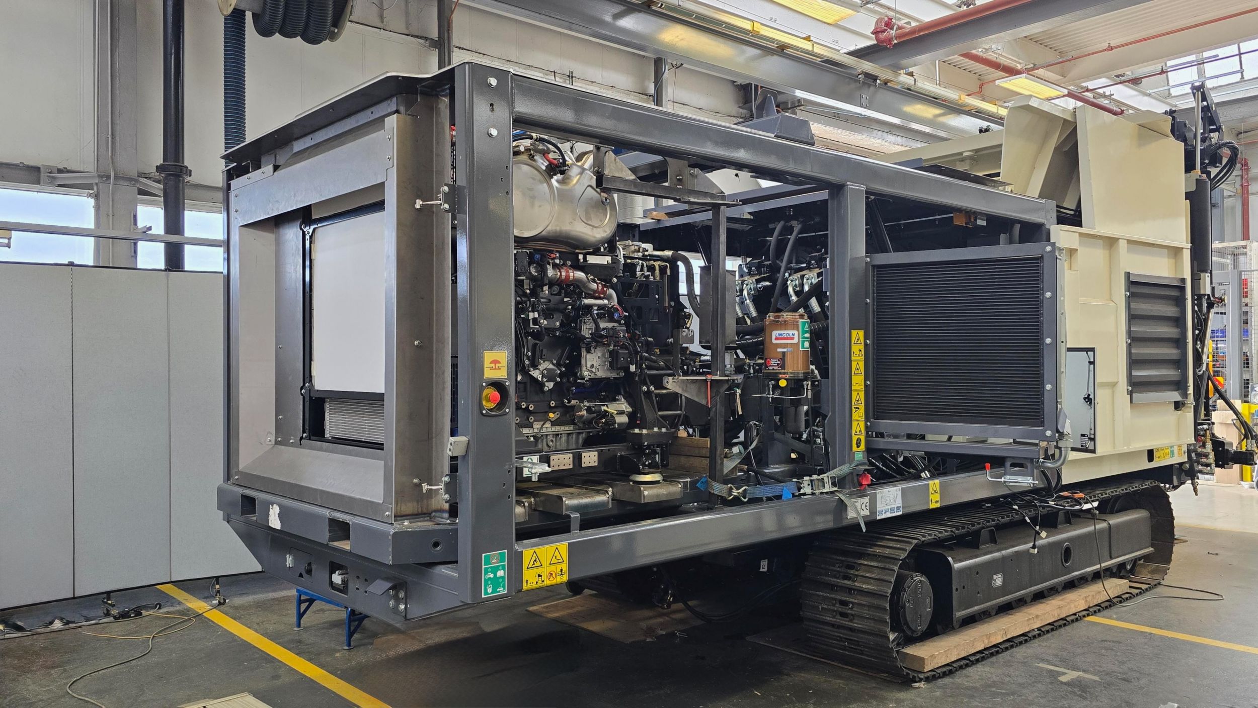 Mobile diesel generator unit with engine compartment open on industrial trailer in factory workshop
