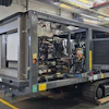 Mobile diesel generator unit with engine compartment open on industrial trailer in factory workshop