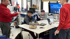 Students and instructor collaborate around a table with engineering equipment during a Field Power Team Design Challenge workshop.