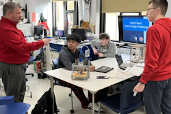 Students and instructor collaborate around a table with engineering equipment during a Field Power Team Design Challenge workshop.