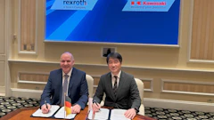 Two businessmen sign documents at formal meeting with Rexroth and Kawasaki logos displayed on screen behind them