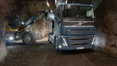 Volvo truck and wheel loader loading material in an underground mining tunnel at night