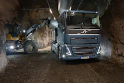 Volvo truck and wheel loader loading material in an underground mining tunnel at night