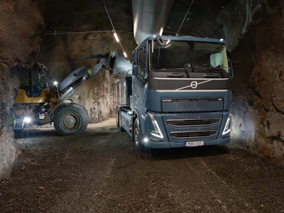 Volvo truck and wheel loader loading material in an underground mining tunnel at night